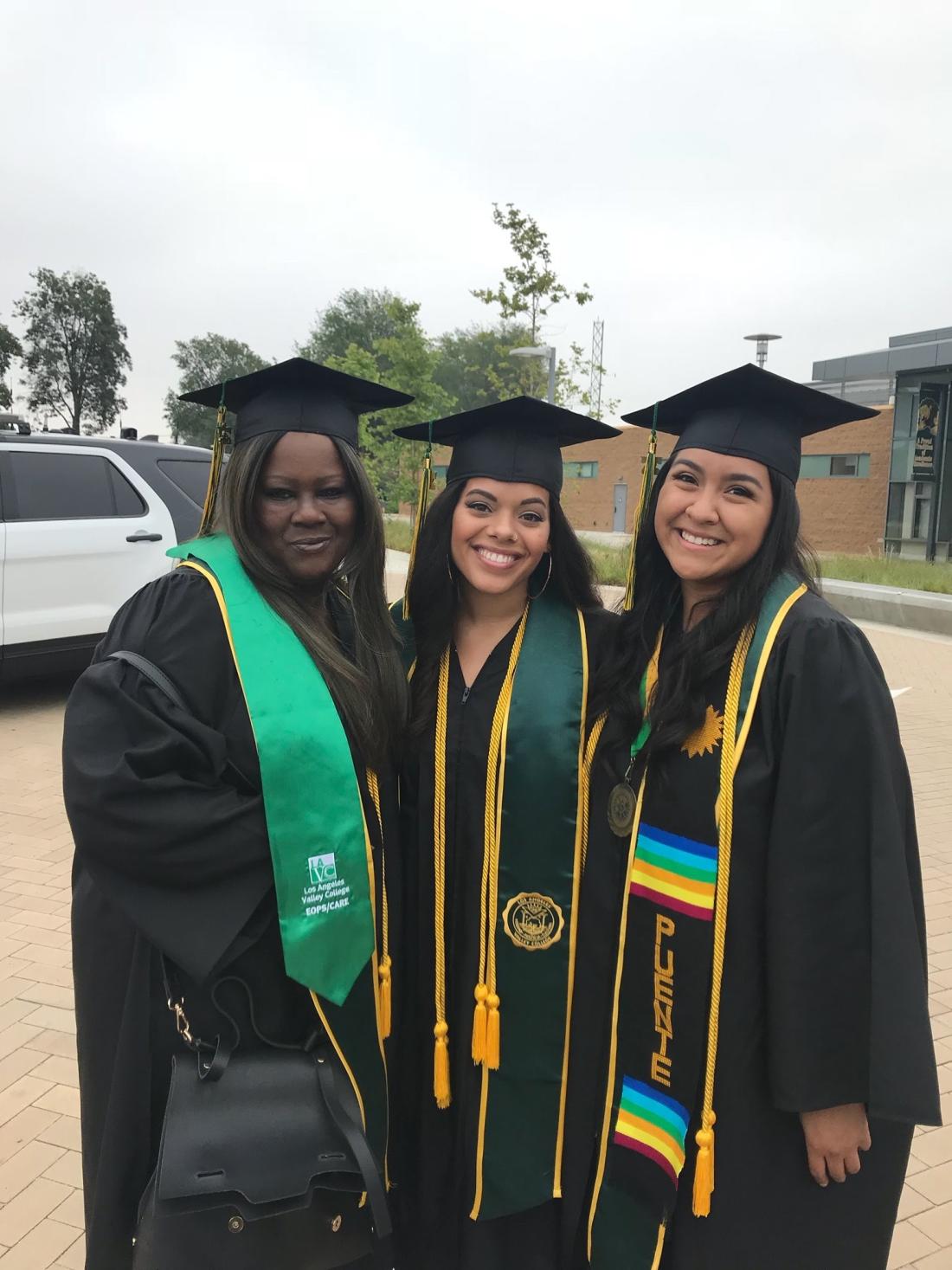 three women smiling in graduation caps and gowns