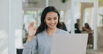 Happy student waving while on a laptop