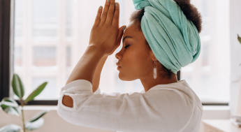 Black women breathing deeply with palms together in front of her forehead