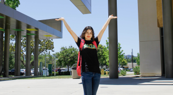 Happy female LAVC student with arms raised up in the air