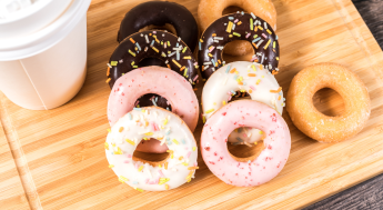 Cup of coffee with an assortment of donuts placed on a wooden cutting board