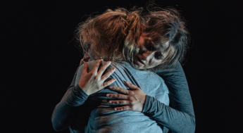 Female actors in a dramatic embrace