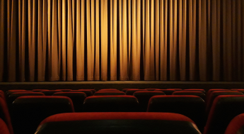 Theater stage with closed gold curtain