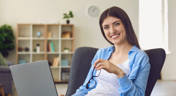 Girl holding glasses with a laptop and smiling at camera
