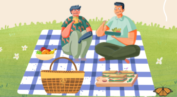 Two students sitting next to a picnic basket and food on a blanket on a grass field