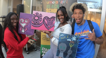 Three Black students posing with their artworks
