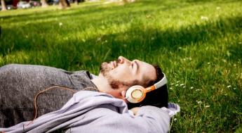 Person laying on grass with headphones on.