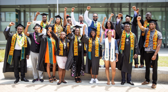 LAVC Umoja Black Scholar graduates wearing caps and gowns with raised right fists