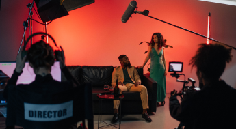 Behind the scenes with director filming a man sitting on couch beside a woman