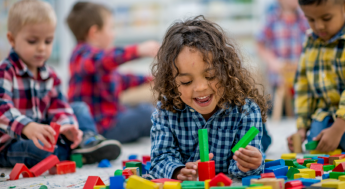 toddler with curly hair playing with blocks