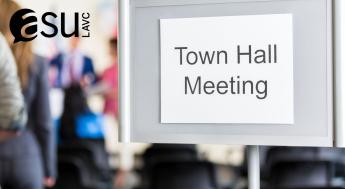 Sign outside of a meeting of blurred people that reads town hall