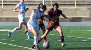 Women's soccer player kicking the ball