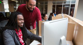 Staff assisting student with enrolling online