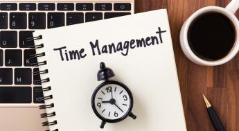 Time management written on a notebook with a clock on top