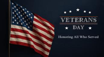 United States flag waving in the air. With the words "Veterans Day, Honoring All Who Served" on the right hand side.
