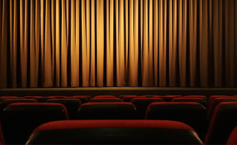 Theater stage with closed gold curtain