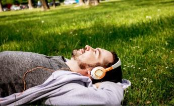 Person laying on grass with headphones on.