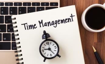 Time management written on a notebook with a clock on top