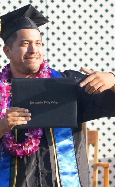 Graduating Student Pointing to his Diploma
