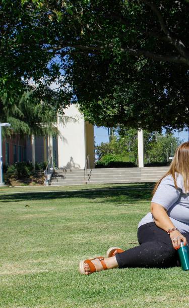 Staff Sitting and Talking on Campus Grass