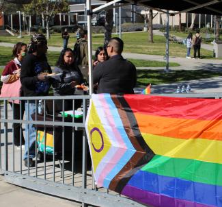 Students talking to counselor next to rainbow flag
