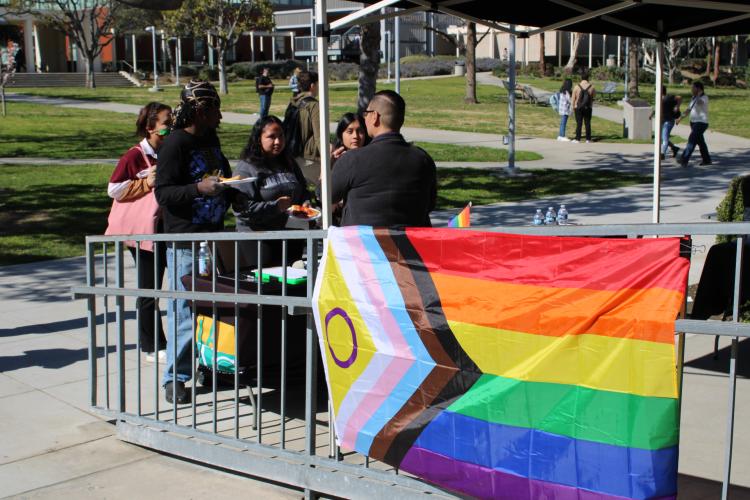 Students talking to counselor next to rainbow flag