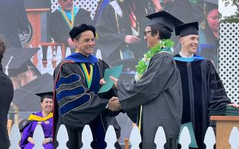 College president shaking a graduating students' hand