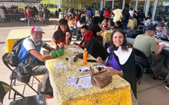 4 people sitting at a table outdoors painting