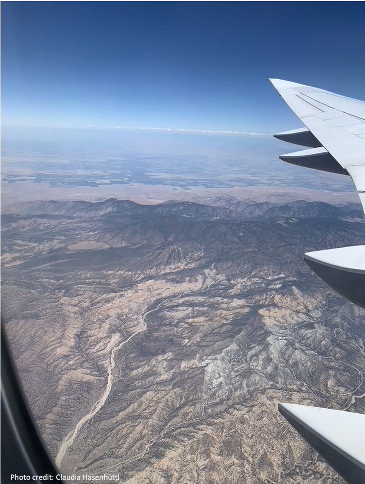 aerial photo of a river valley and an airplane wing