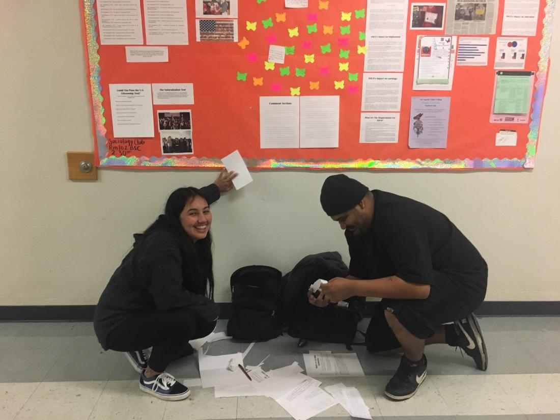 Two people decorating a billboard
