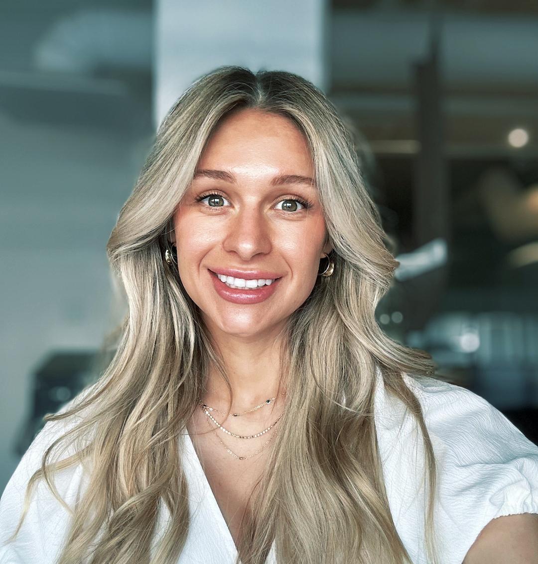 Woman with long hair smiling in front of blurred background