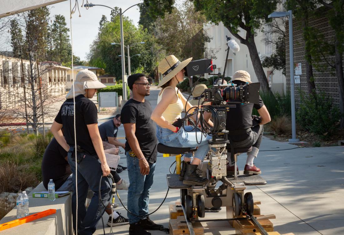 Cinema/Media Arts students on a dolly shooting a student film on campus.