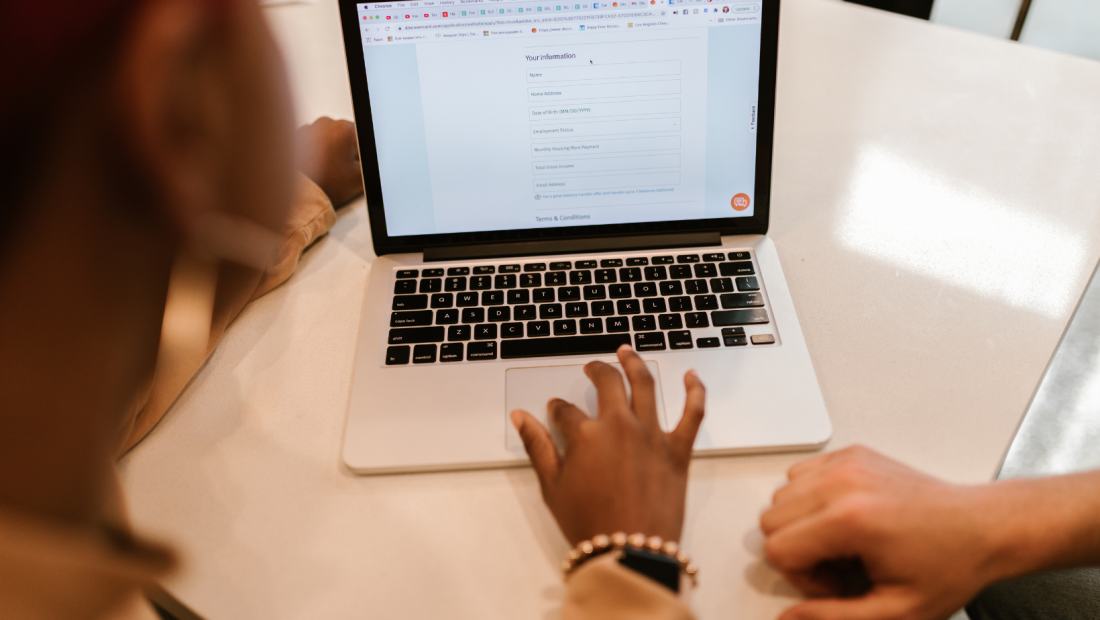 a hand on laptop keyboard filling out a form