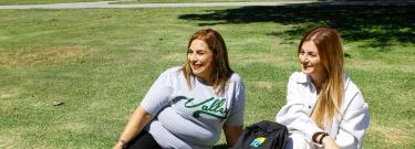 Two female students sitting on Monarch Square Lawn