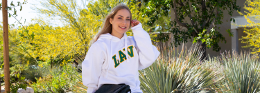 Female student wearing an LAVC sweatshirt sitting on bench smiling at the camera