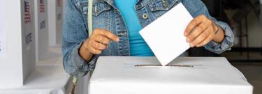 A woman casting her ballot into a ballot box