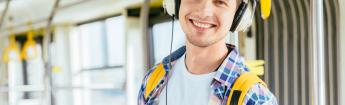 Male student with backpack and headphones riding the bus